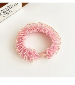 Dettaglio di elastico rosa in tulle con bordo dorato e perla liscia in resina