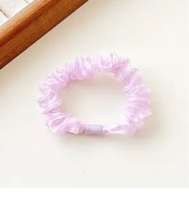 Macro detail of lavender iridescent organza scrunchie with pleated texture and round clasp