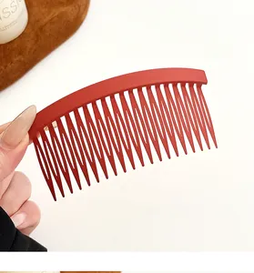 Détail du peigne à cheveux en résine rouge mat montrant les dents fines et l'ergonomie