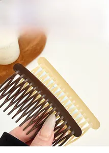 Close-up of matte resin hair side combs in brown and amber on a decorative tray