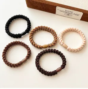 Close-up of five braided elastic hair ties in neutral earth tones with plastic clasps