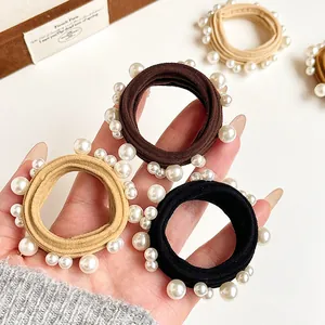Elastic hair ties set with faux pearls in black and beige, shown in a gift box