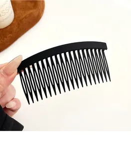 Gros plan d'un peigne à cheveux noir mat avec 17 dents tenu à la main pour le coiffage
