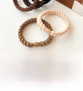 Close-up of thick braided hair ties in coffee and nude tones with matte finish buckles