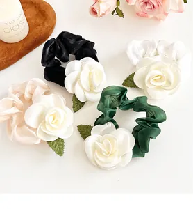 Détail de chouchous camélia multicolores en tissu noir, blanc, rose et vert élégant