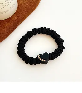 Detailed view of a black elastic scrunchie with a heart-shaped rhinestone charm