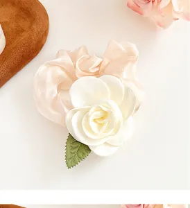 Détail macro d'un chouchou fleur de camélia crème avec tissu aux reflets nacrés