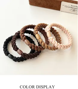 Detail of five thick woven elastic hair ties in neutral tones with matching beads