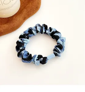 Detail eines blau-schwarzen Satin-Scrunchie mit Zickzackmuster und Verbinder