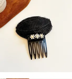 Détail d'un coussinet de volume noir avec dentelle et trois ornements floraux en strass