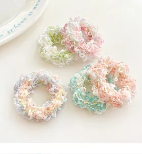 Detailed view of four macaron-colored fuzzy hair ties in soft textured fabric on a table
