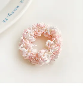 Close-up of pink and white crocheted scrunchie showing detailed knitted yarn texture
