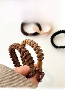 Close-up of thick woven elastic hair ties with oval beads in coffee and beige colors