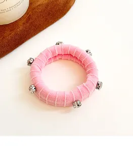Vue détaillée d'un chouchou rose en maille avec des ornements en strass brillants