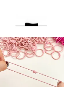 Detail of pink elastic hair band being stretched to show high elasticity and woven texture
