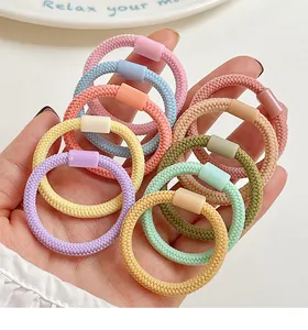 Détail de chouchous élastiques colorés aux tons macaron portés à la main pour enfants