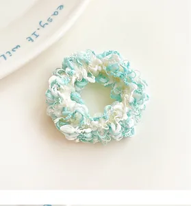 Detailed close-up of a blue and white fuzzy hair scrunchie with soft plush texture