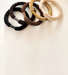 Detail of four thick elastic woven hair ties in earth-toned colors and matte connectors