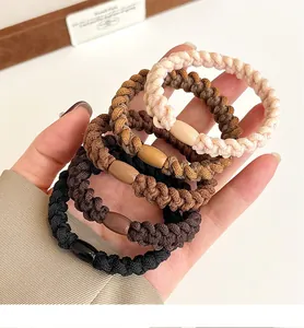 Close-up of five thick elastic woven hair ties in earth tones held by a hand
