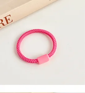 Primer plano de goma de pelo elástica rosa brillante con cuenta rectangular en fondo crema