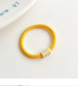 Close-up of a high-elastic bright yellow ribbed hair tie with a beige matte buckle
