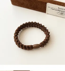 Detail of coffee-colored braided hair tie with a shiny matching decorative bead