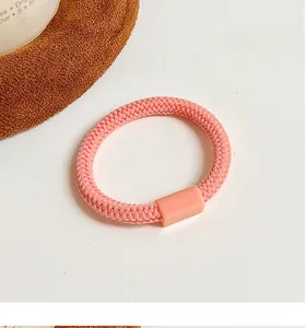 Détail d'un élastique à cheveux rose clair épais avec texture tissée et attache