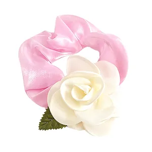 Chouchou élégant en satin rose avec une fleur de camélia blanche et une petite feuille
