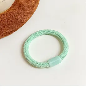 Détail d'un élastique à cheveux tressé vert menthe avec une boucle en résine