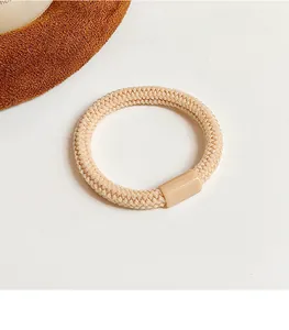 Détail d'un élastique à cheveux beige tressé avec un fermoir en résine lisse