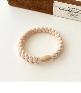 Detailed macro view of cream braided elastic hair tie with a smooth brown resin buckle