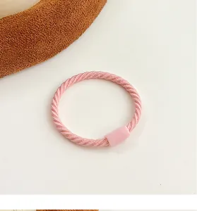 Close-up of a pink elastic hair tie with spiral texture and matching plastic buckle