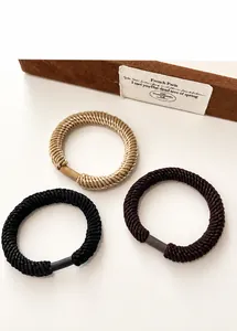 Close-up of thick elastic braided hair ties in black, dark brown, and gold colors