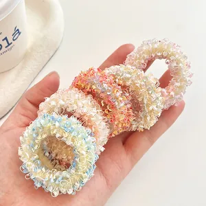 Five colorful pastel scrunchies made of soft plush fabric held in hand on white desk