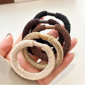 Detailed shot of five elastic braided hair ties in neutral earth tones held in hand