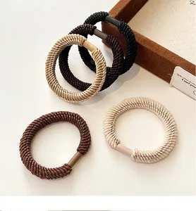 Detailed view of elastic woven hair ties in black, brown, khaki, and beige tones