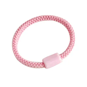 Coletero elástico rosa macaron con cuenta decorativa a juego sobre un fondo blanco puro
