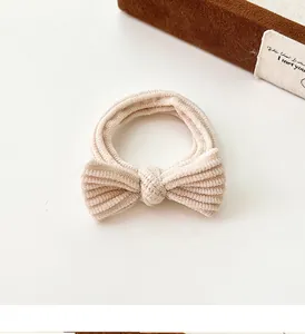 Detail of cream bow hair tie with textured rib fabric showing soft elastic material