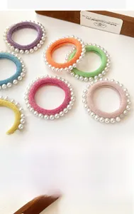 Détail de 7 chouchous colorés à paillettes avec perles sur fond beige clair