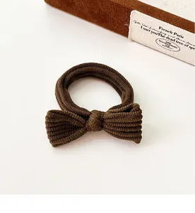 Detail of dark brown ribbed fabric hair tie featuring a minimalist bow knot design