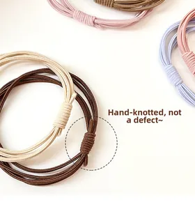 Detail of hand-knotted elastic hair bands in soft colors on a clean white background
