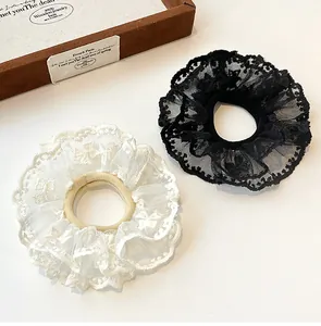 Detail of elegant black and white double-layer lace scrunchies on a soft surface