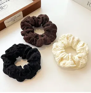 Detail view of elastic scrunchies in black, dark coffee and creamy white colors