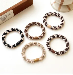 Detail of five earth-toned woven hair ties with durable elastic bands and oval connectors