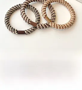Close-up of woven coffee and beige hair ties showing elastic spiral texture and durability