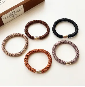 Detail of high-elasticity braided hair ties with metallic gold buckles in five coffee tones