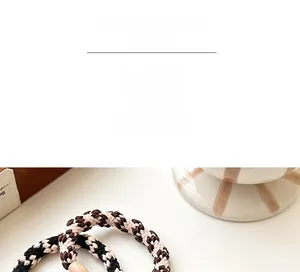 Detailed view of woven checkered hair ties in black, white, and coffee colors