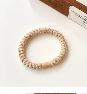 Detailopname van gevlochten elastische haarelastiek met spiraaltextuur in beige