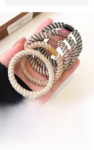 Close-up of elastic woven hair ties in neutral tones held in hand to show texture