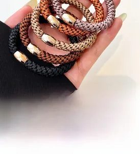 Close-up of five thick elastic hair ties in neutral tones with gold metal buckles